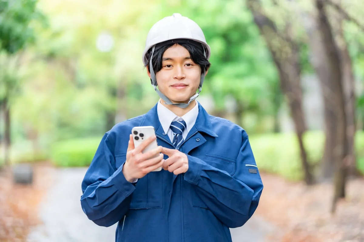 スマートフォンで電気工事士の求人を検索する若手作業員