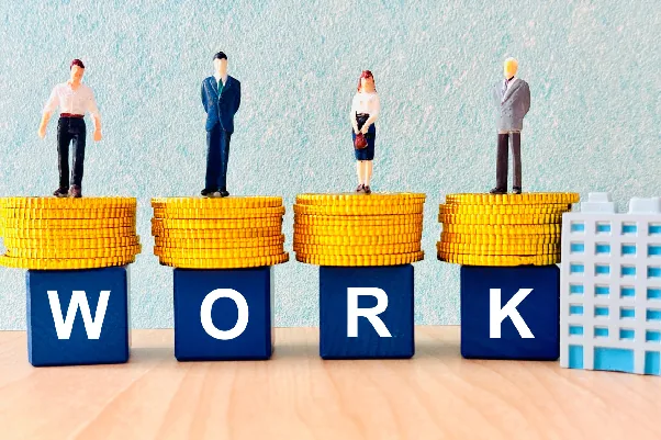 コインの上に立つ人形と「WORK」の文字ブロック